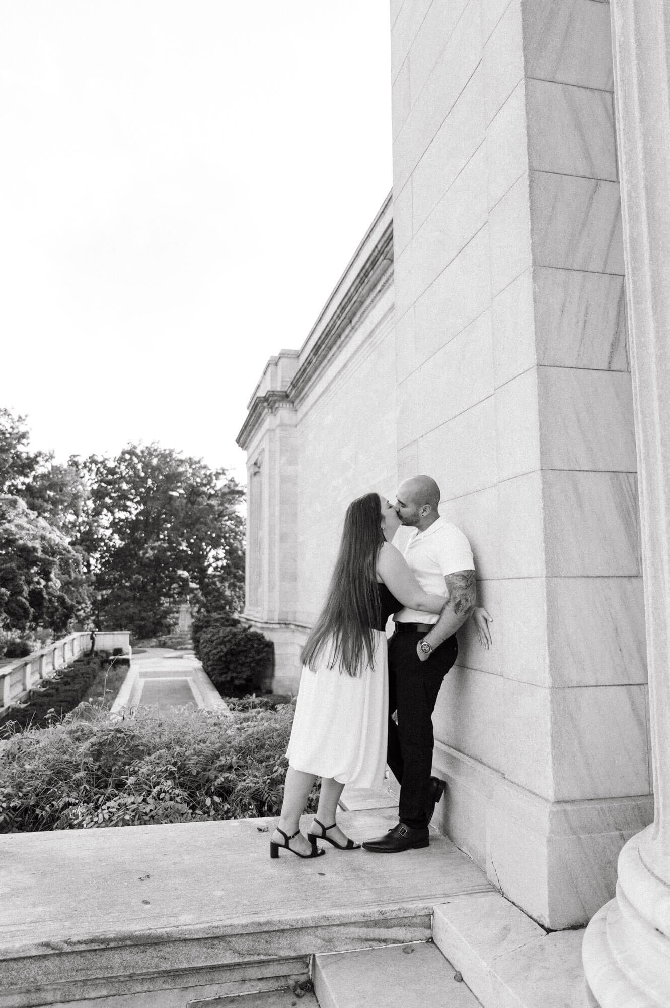 Couple sharing a kiss beside the museum building.
