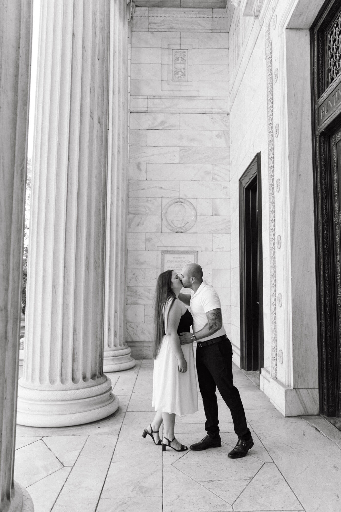 Couple kissing between marble columns.